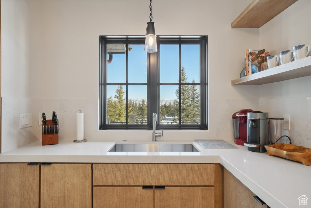 Kitchen with a sink, light countertops, decorative light fixtures, and open shelves