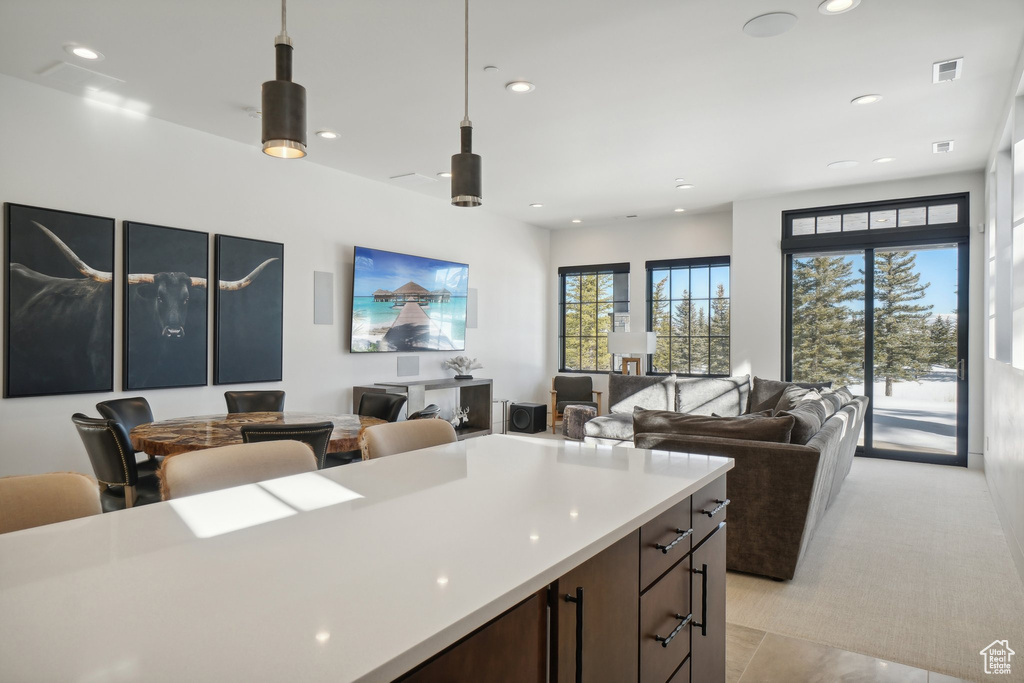 Kitchen featuring plenty of natural light, open floor plan, recessed lighting, pendant lighting, and light countertops
