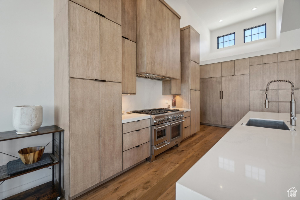 Kitchen with double oven range, a sink, light brown cabinetry, modern cabinets, and light countertops