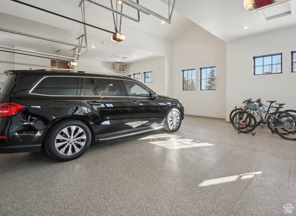 Garage with a garage door opener, recessed lighting, and baseboards