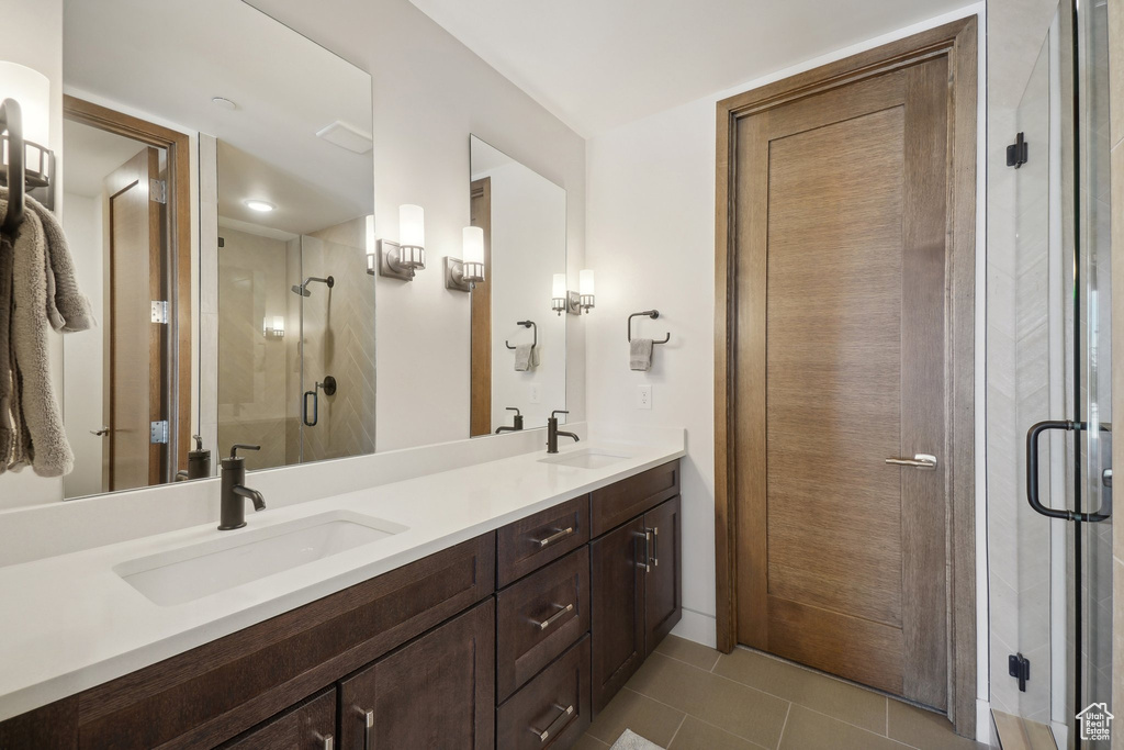 Full bathroom featuring double vanity, a shower stall, and tile patterned flooring