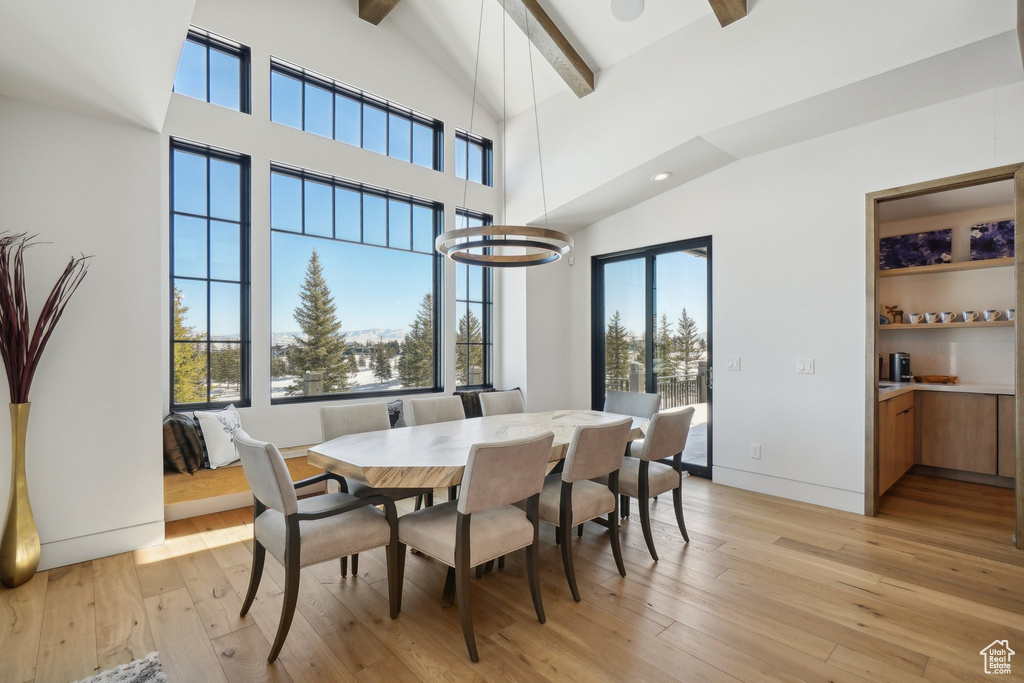Dining room with beam ceiling, light wood-style flooring, and high vaulted ceiling
