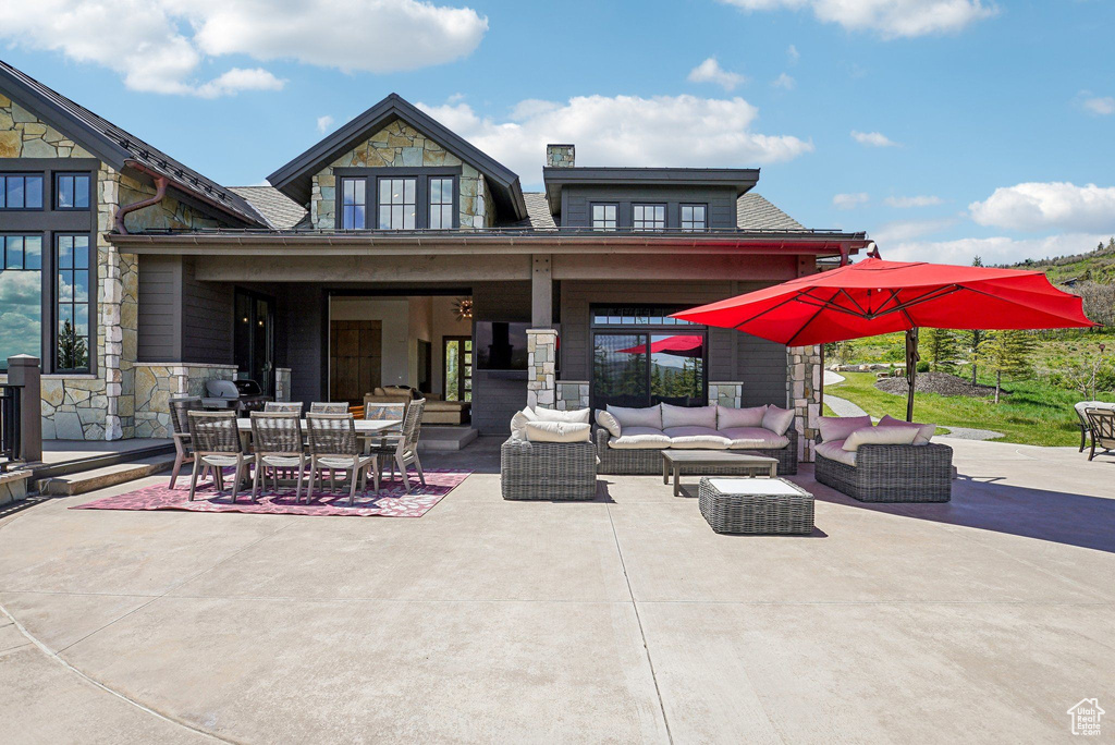Back of property featuring stone siding, an outdoor living space, a patio area, and outdoor dining space