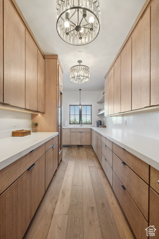 Kitchen featuring a chandelier, light countertops, light brown cabinets, light wood-style floors, and open shelves