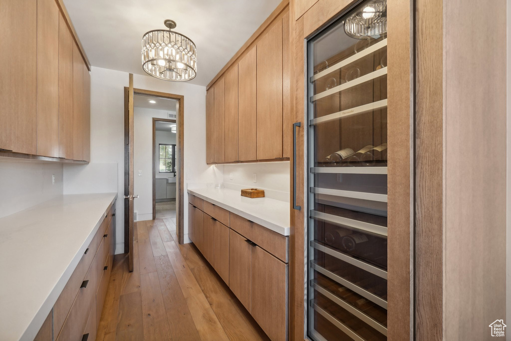Kitchen with light countertops, light wood-type flooring, a chandelier, and modern cabinets
