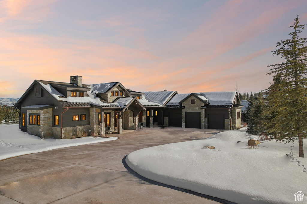 View of front of house with stone siding, a chimney, an attached garage, and a porch