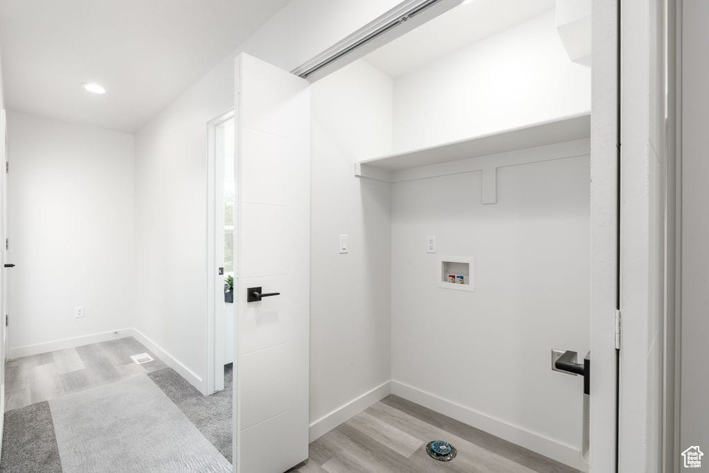 Laundry room featuring washer hookup and light hardwood / wood-style flooring