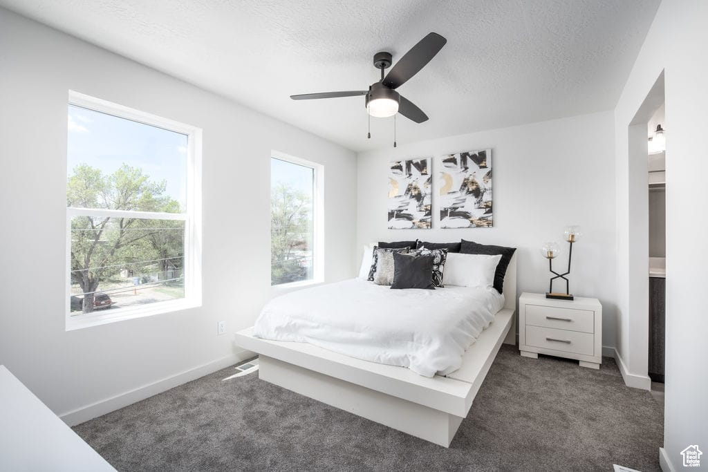 Carpeted bedroom featuring a textured ceiling and ceiling fan