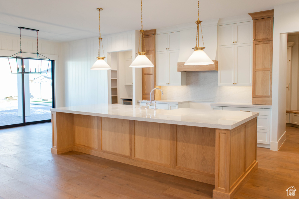 Kitchen featuring white cabinetry, a large island, sink, and light hardwood / wood-style floors