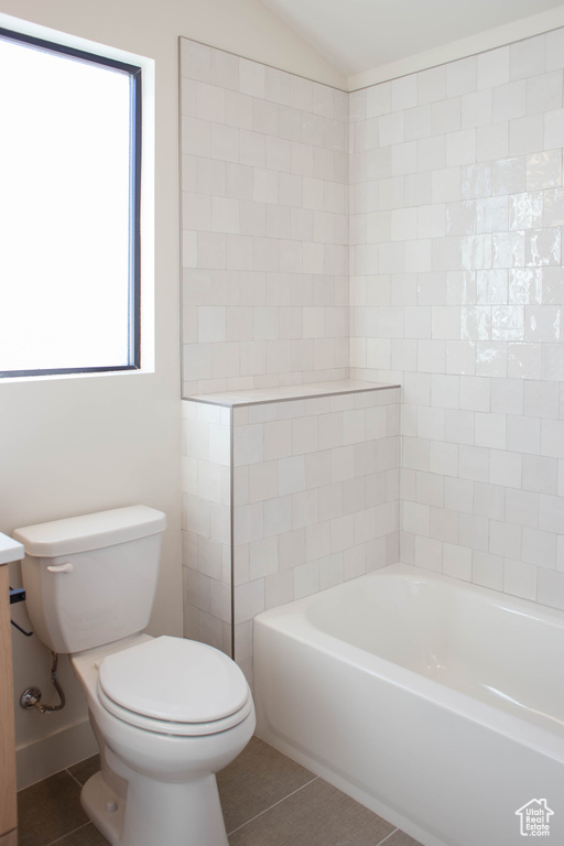 Full bathroom with lofted ceiling, toilet, vanity, shower / bath combination, and tile patterned flooring