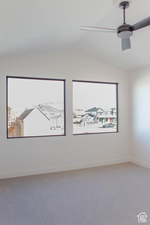 Spare room featuring vaulted ceiling, ceiling fan, and carpet floors