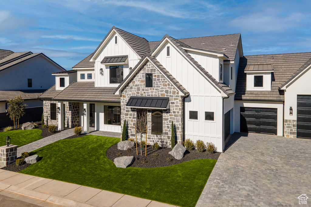 Modern farmhouse featuring a front lawn and a garage