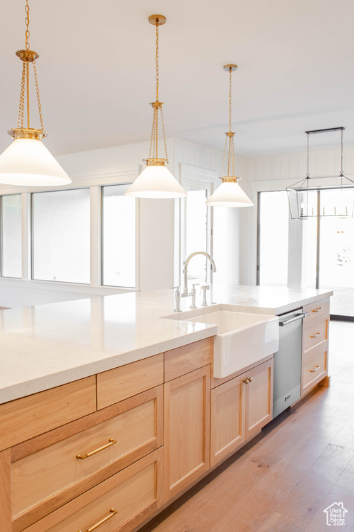 Kitchen featuring pendant lighting, sink, light hardwood / wood-style flooring, stainless steel dishwasher, and light brown cabinets