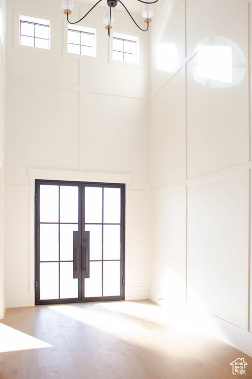 Interior space with french doors, a towering ceiling, and an inviting chandelier