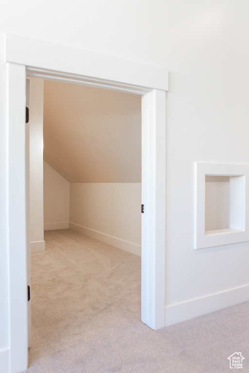 Additional living space with vaulted ceiling and light carpet