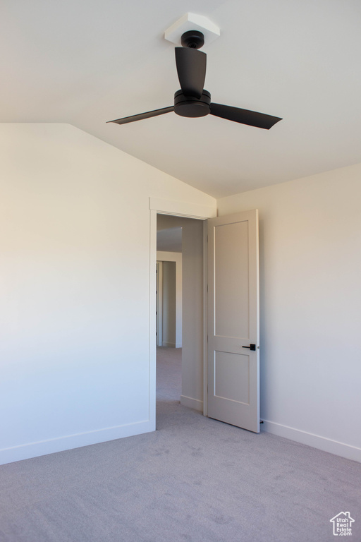 Carpeted spare room featuring ceiling fan and vaulted ceiling