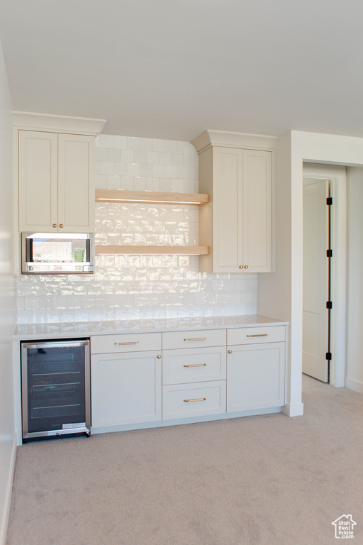 Kitchen with white cabinets, tasteful backsplash, light carpet, and wine cooler