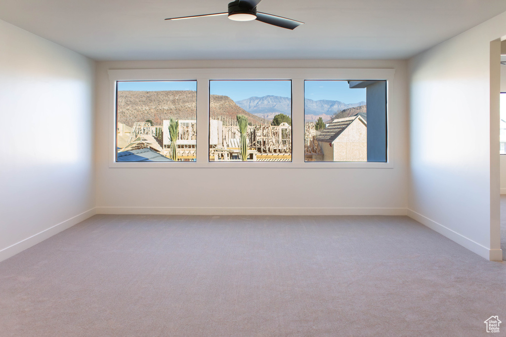 Carpeted empty room with a mountain view and ceiling fan