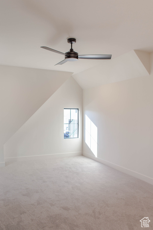 Additional living space with ceiling fan, vaulted ceiling, and light carpet