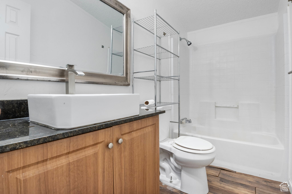 Full bathroom featuring tub / shower combination, a textured ceiling, hardwood / wood-style floors, vanity, and toilet