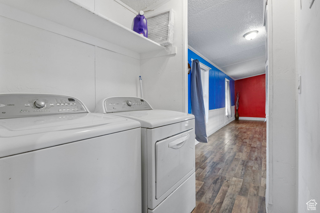 Washroom featuring a textured ceiling, dark wood-type flooring, and washer and dryer