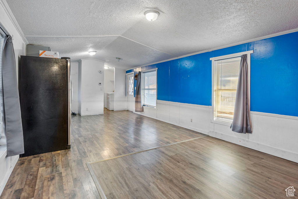 Unfurnished living room with plenty of natural light, crown molding, and wood-type flooring