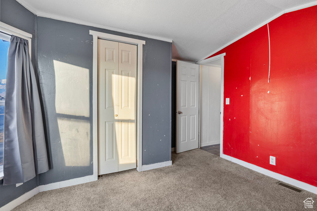 Unfurnished bedroom featuring vaulted ceiling, ornamental molding, and carpet floors