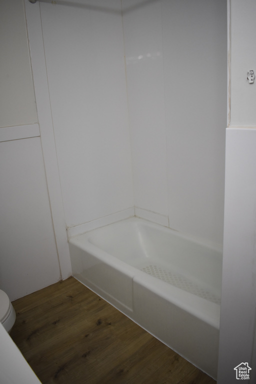 Bathroom with hardwood / wood-style flooring, a tub, and toilet
