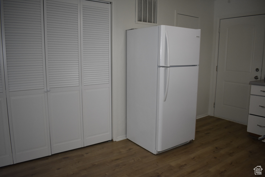 Kitchen featuring white cabinetry, hardwood / wood-style floors, and white refrigerator