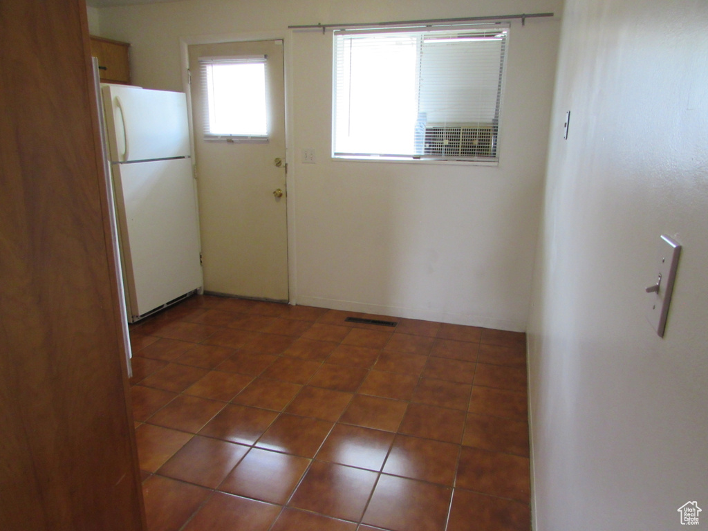 Interior space with white fridge and dark tile patterned floors