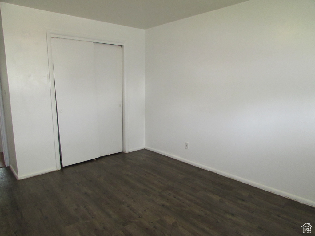 Unfurnished bedroom with a closet and dark wood-type flooring