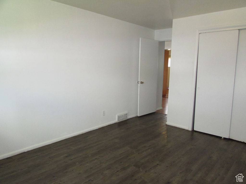 Unfurnished bedroom featuring dark wood-type flooring and a closet