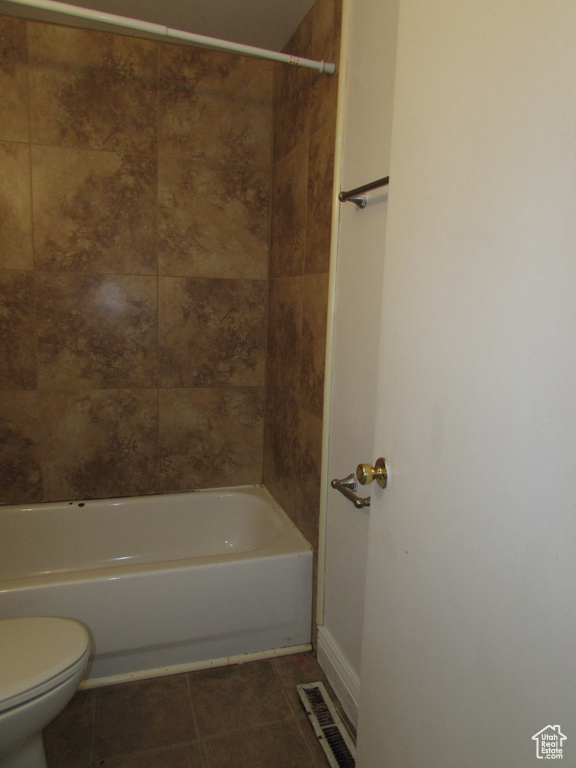 Bathroom featuring tile patterned floors, toilet, and tiled shower / bath