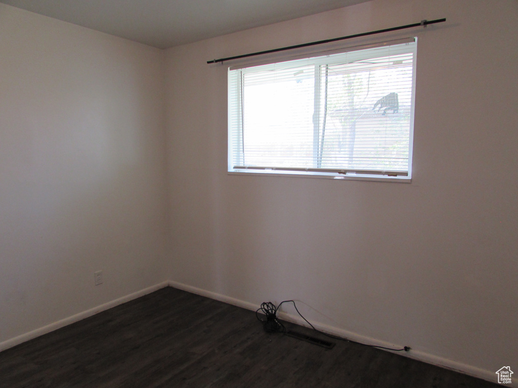 Empty room featuring a healthy amount of sunlight and dark hardwood / wood-style flooring