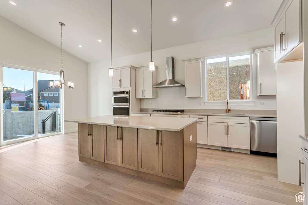 Kitchen with wall chimney range hood, white cabinets, and a center island