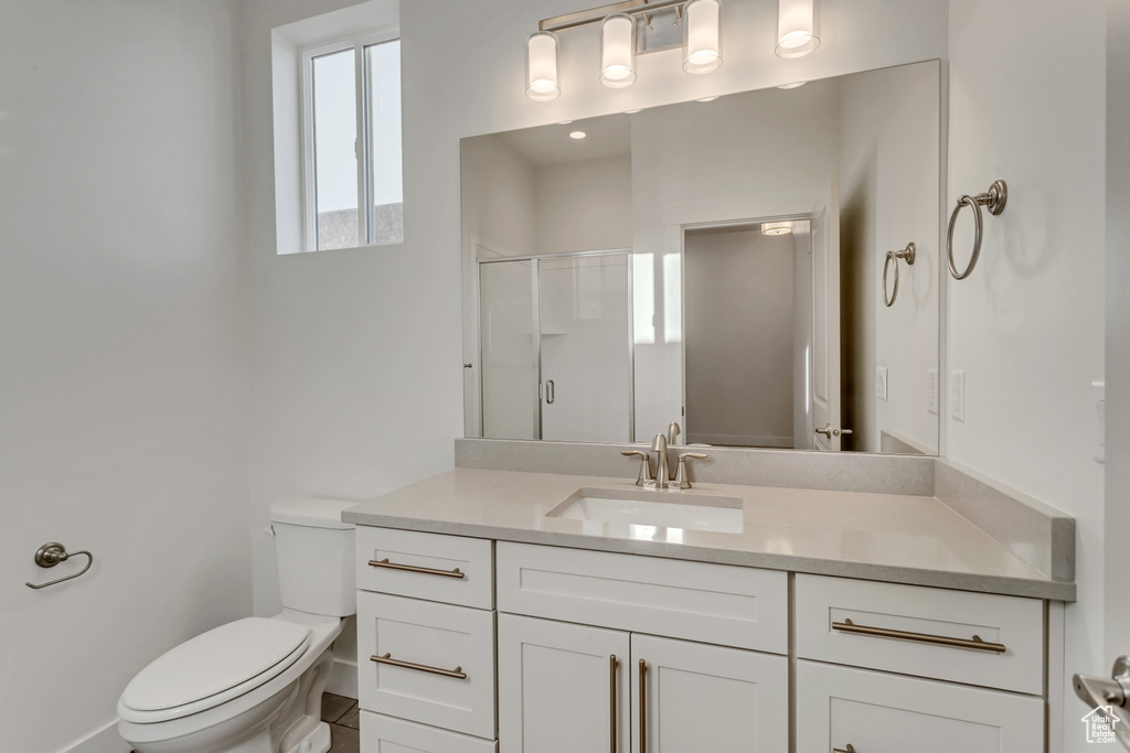 Bathroom with an enclosed shower, vanity, and toilet