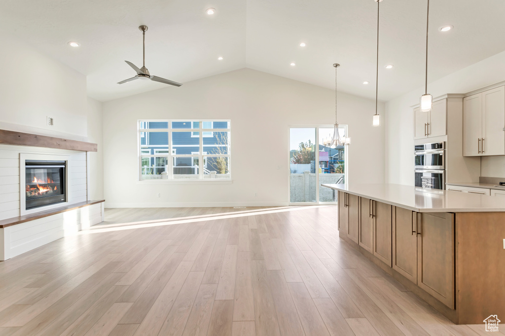 Kitchen featuring a spacious island, pendant lighting, light wood-type flooring, white cabinets, and double oven