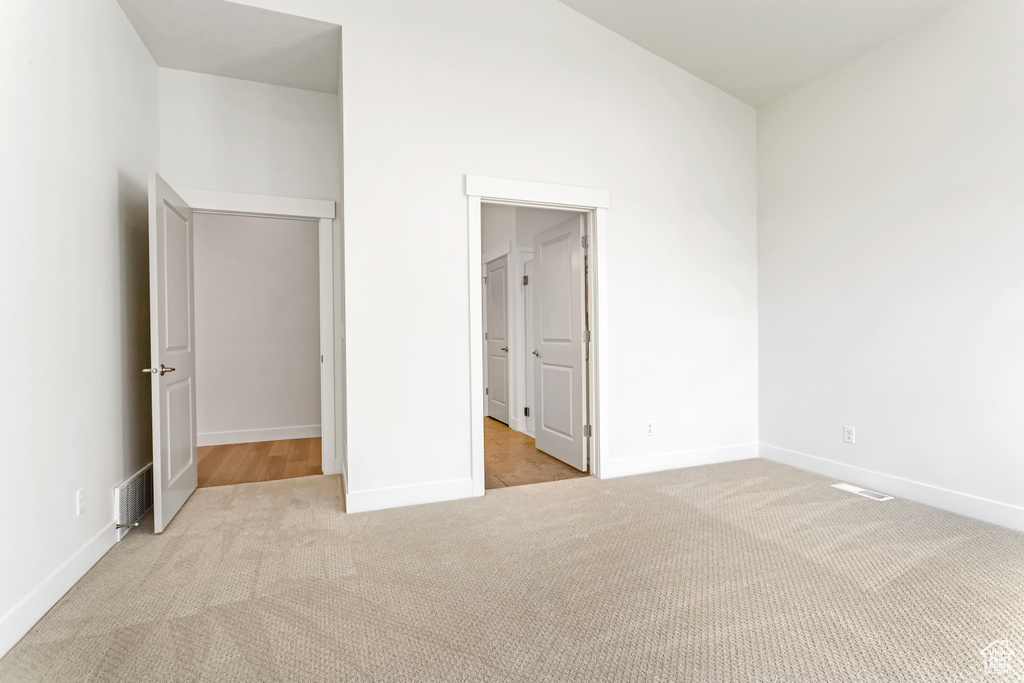 Unfurnished bedroom featuring light carpet and a closet