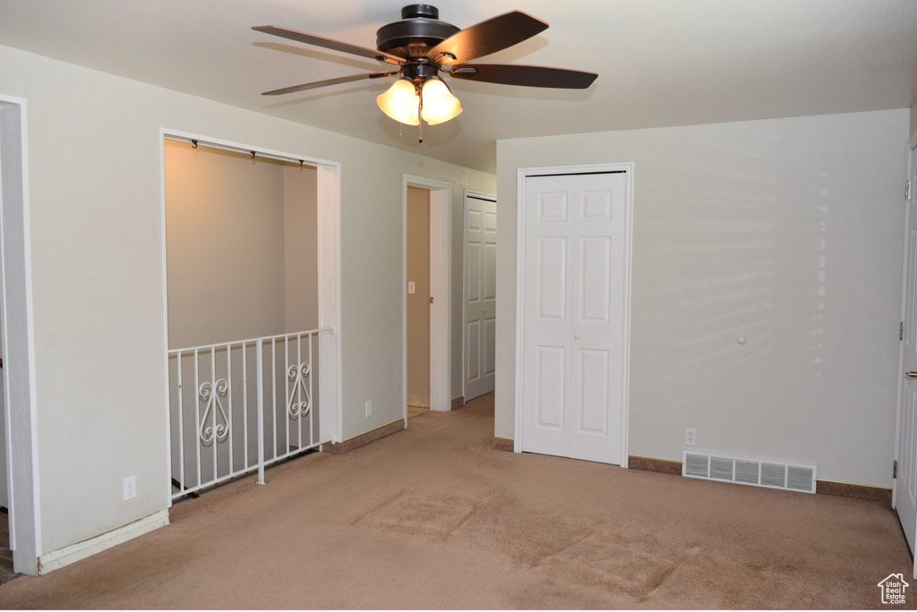 Unfurnished bedroom featuring ceiling fan and light carpet