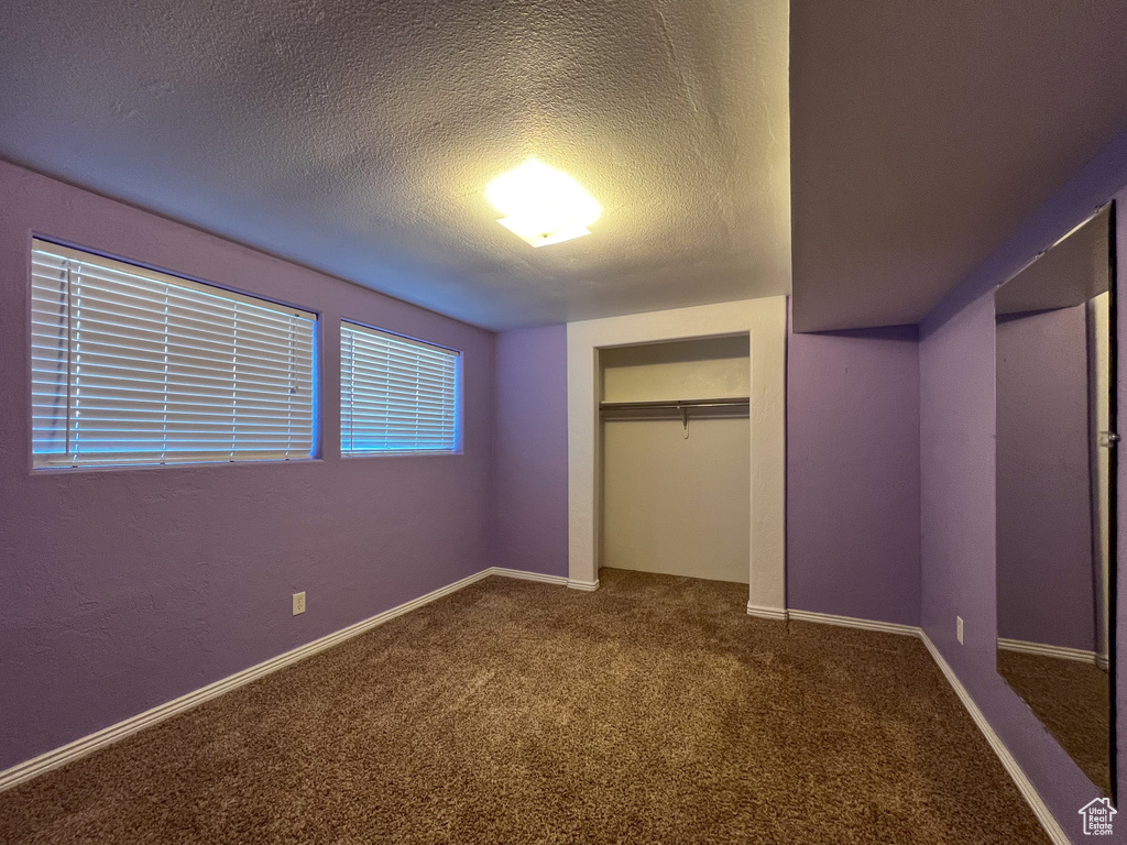 Unfurnished bedroom featuring a closet, a textured ceiling, and carpet flooring