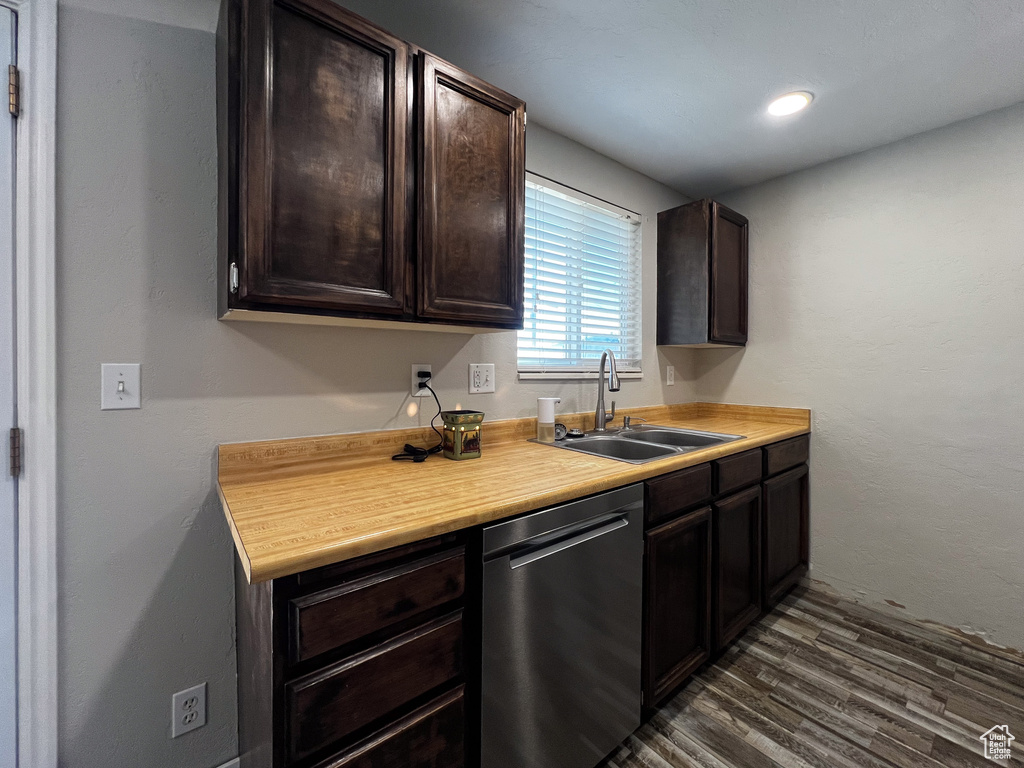 Kitchen featuring sink, dark wood-type flooring, dark brown cabinets, and dishwasher