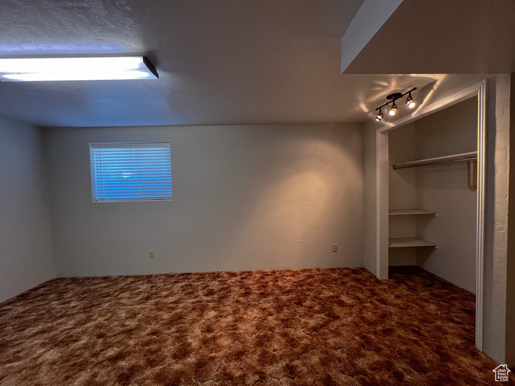 Unfurnished bedroom with track lighting, a closet, and carpet