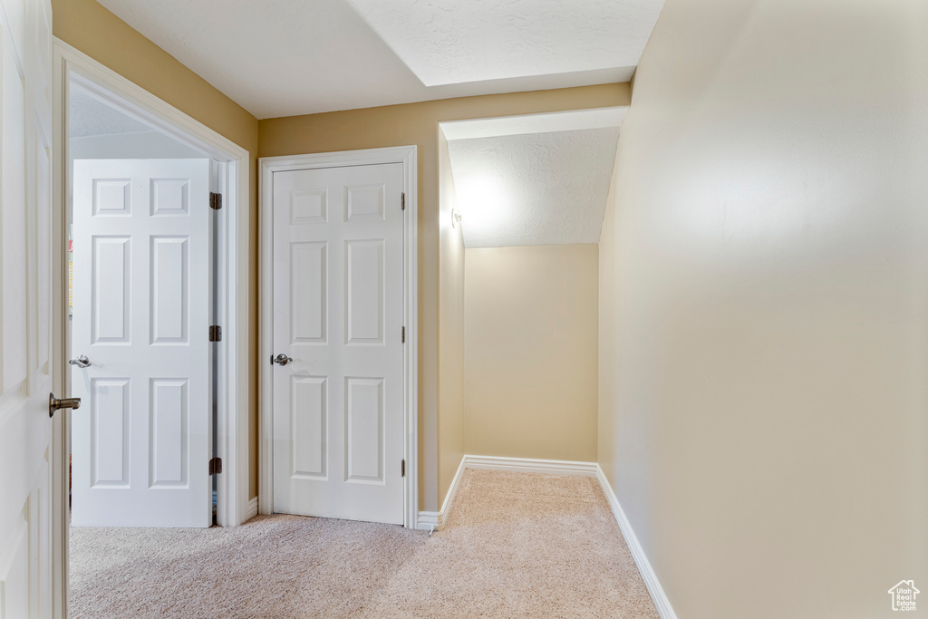 Hallway featuring light colored carpet