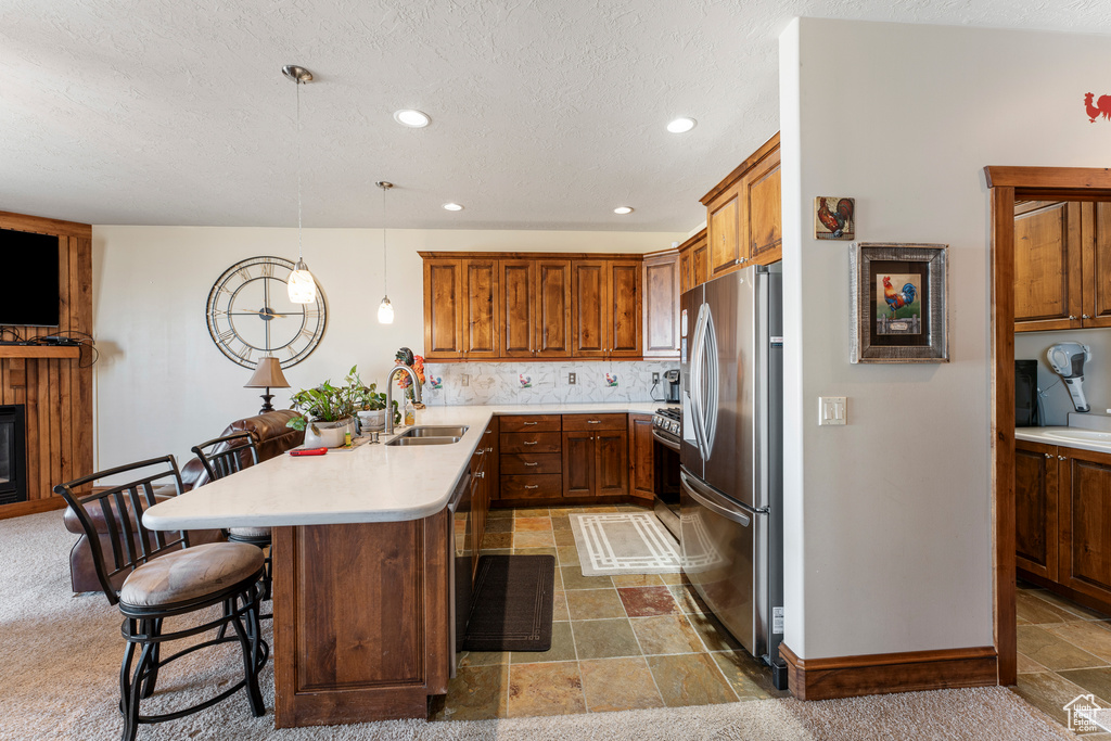 Kitchen with pendant lighting, sink, stainless steel fridge, a breakfast bar area, and kitchen peninsula