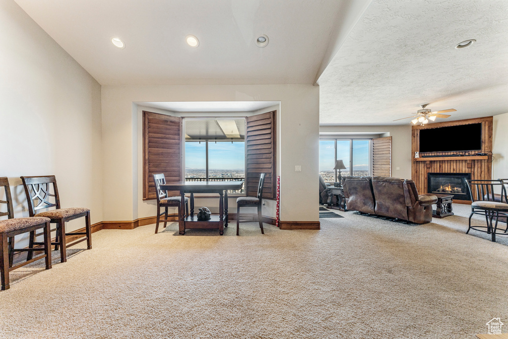 Carpeted dining room featuring a textured ceiling, a fireplace, and ceiling fan