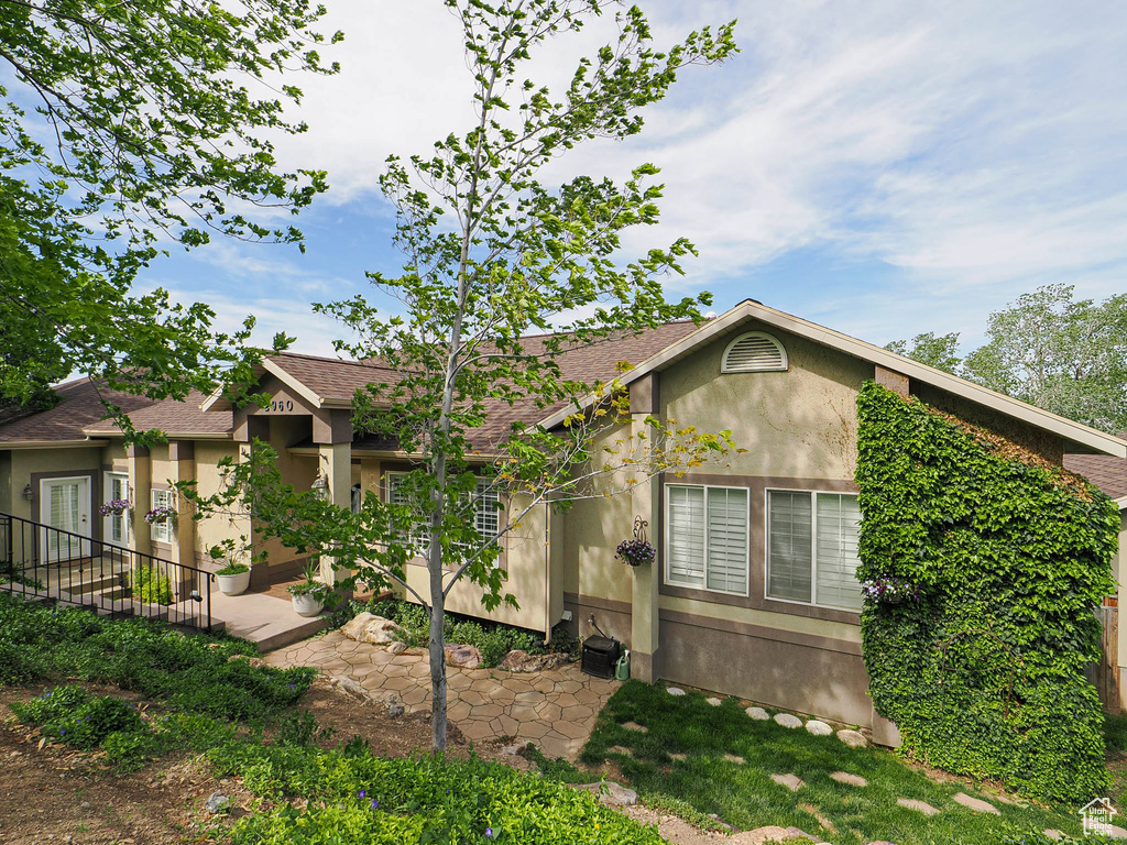 View of front of house with stucco siding and roof with shingles