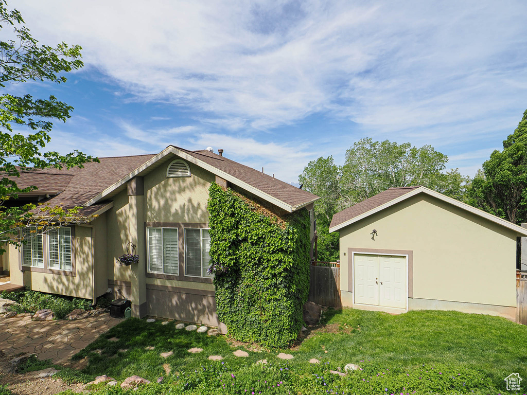 View of home's exterior with a shingled roof and an outbuilding
