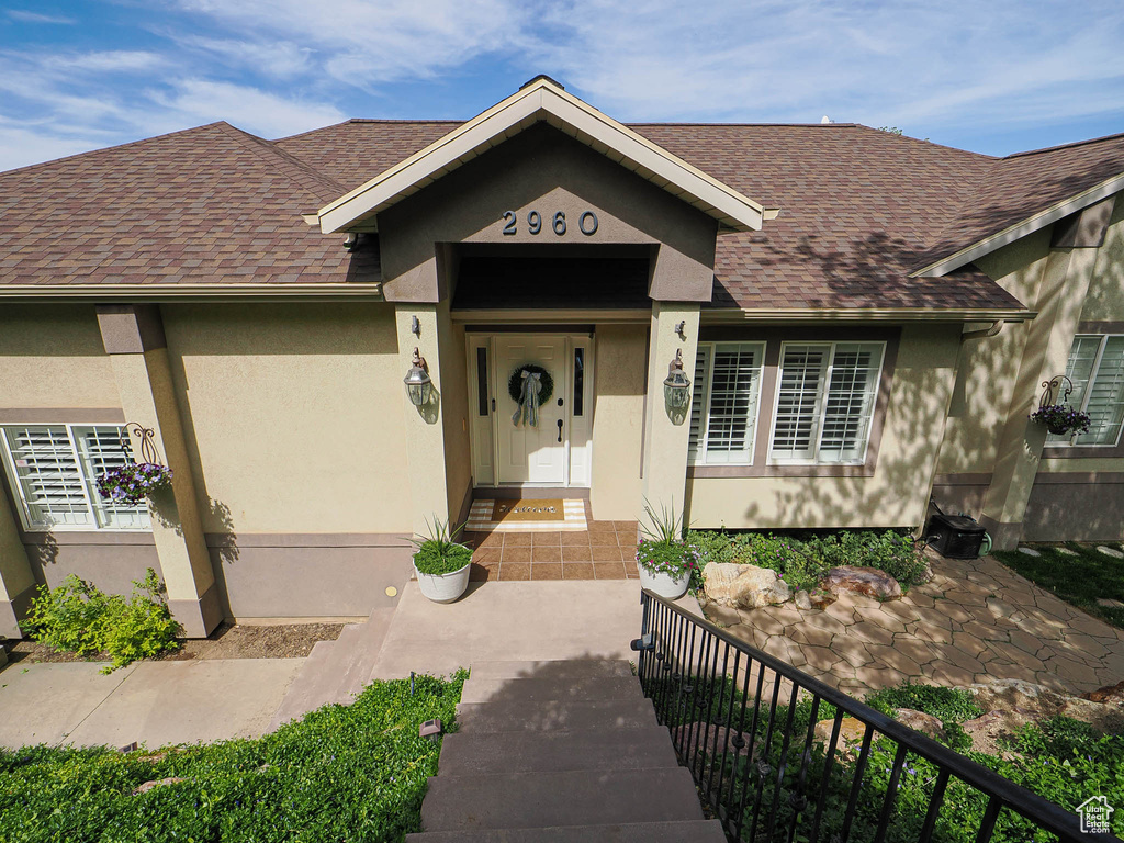 View of front of home featuring roof with shingles and stucco siding