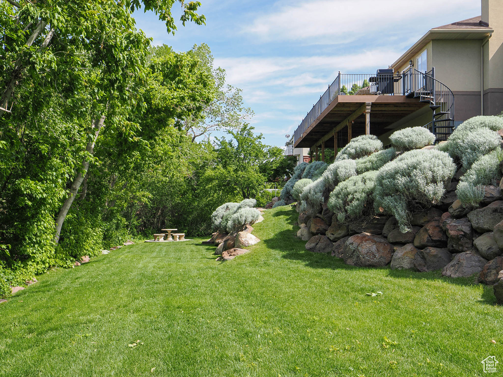 View of green lawn with a wooden deck and stairs