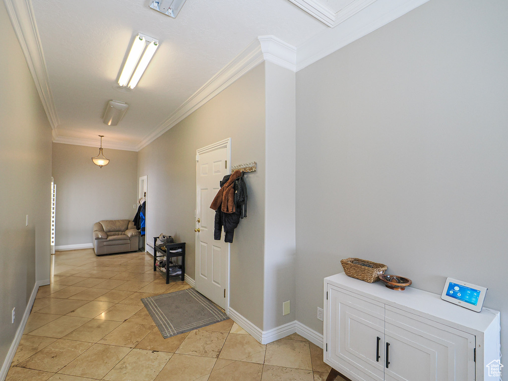 Foyer entrance with crown molding, light tile patterned flooring, and baseboards